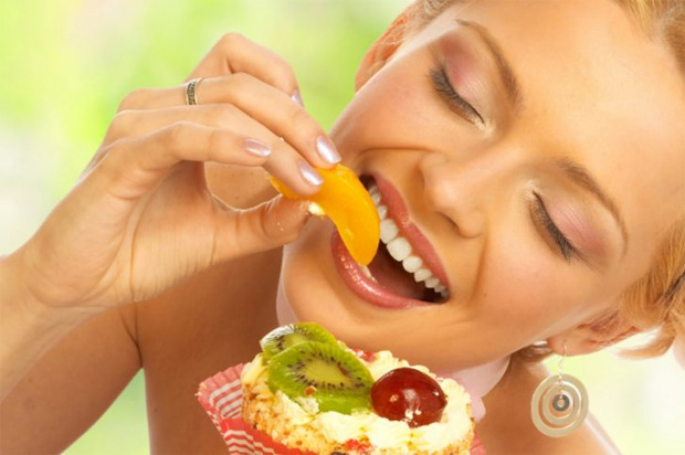 Счастливая девушка с удовольствием ест свежие экзотические фрукты из миски