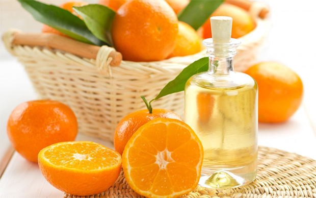 На столе корзина с апельсинами и разрезанные плоды с бутылкой апельсинового масла