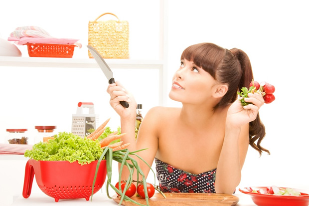 Девушка держит в одной руке нож, в другой пучок редиса и готовится делать салат
