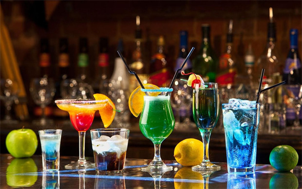 На барной стойке в кафе в ряд выставлены несколько видов алкогольных коктейлей