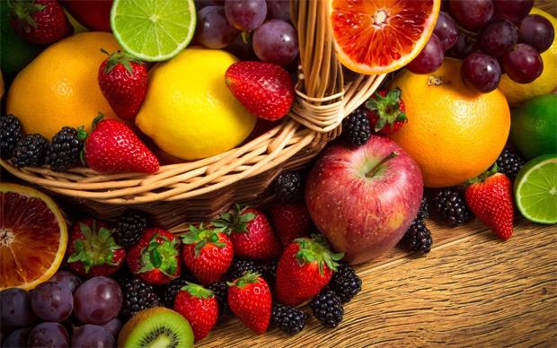 На столе большая плетеная корзина со спелыми фруктами и ягодами