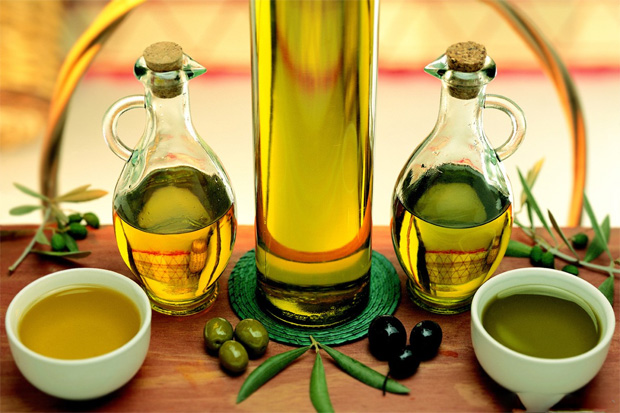 На столе две бутылочки и две мисочки из масла оливок и маслин