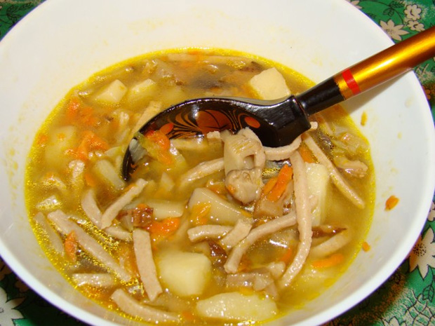 В белой тарелке с деревянной ложкой суп на курином бульоне с картошкой