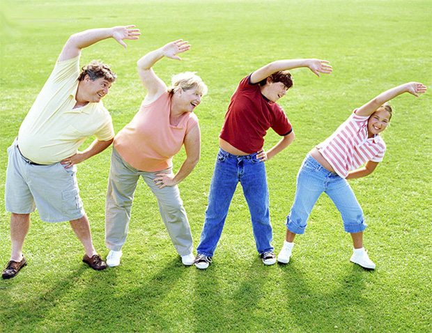 Счастливая семья из четырех человек выполняет физические упражнения на природе