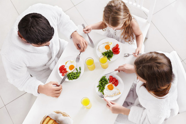 Семья из трех человек завтракает за столом полезной сбалансированной пищей