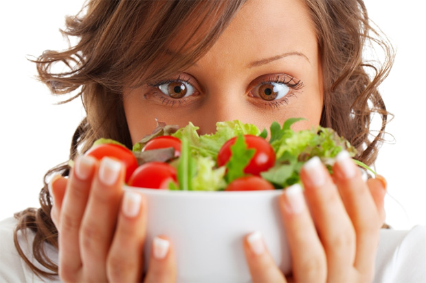 Девушка удивленными глазами смотрит на миску с витаминным салатом, которую держит в руках