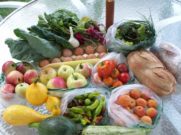 на уличном столике в целлофановых пакетах разложены свежие овощи, фрукты и зелень