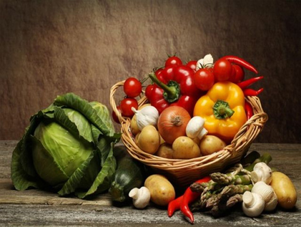 На столе кочан капусты и плетеная корзина с различными овощами
