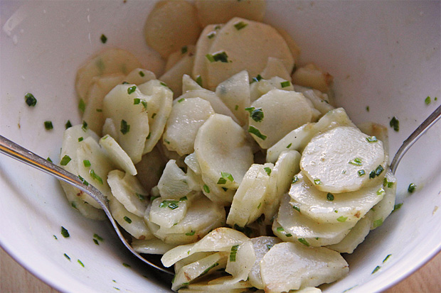 В глубоком белом салатнике нарезанный и заправленный топинамбур с зеленью