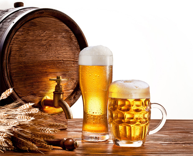 На фоне небольшого деревянного бочонка стоит бокал и кружка с пивом