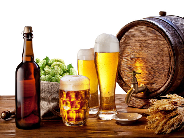 На столе стоит деревянный бочонок, бутылка, два бокала и кружка с пивом
