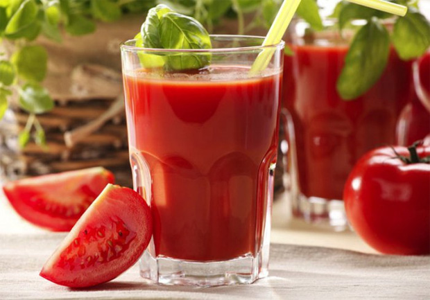 На столе два стакана с томатным соком и свежий помидор дольками и целый