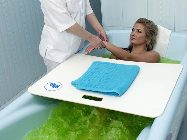 Девушка под присмотром врача в лечебном учреждении принимает минеральную ванну