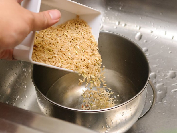 На кухне в раковине стоит кострлюя с водой, куда высыпают зерна риса из миски