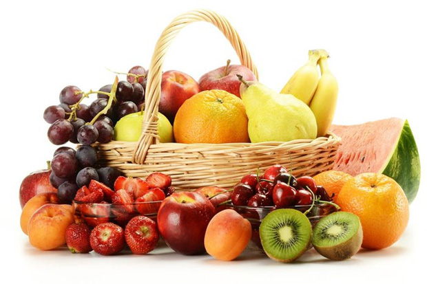 На столе большая корзина с сочными фруктами и спелыми ягодами