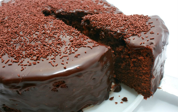 На большом блюде шоколадный торт с глазурью и шоколадной посыпкой