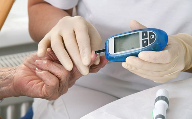 Медицинский работник в перчатках измеряет сахар в крови пациента прибором