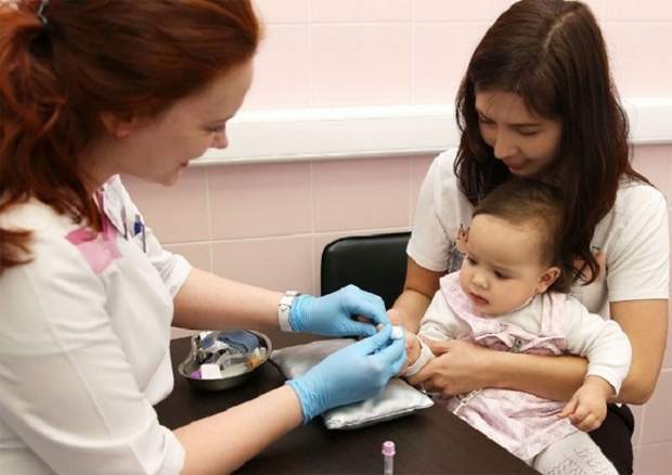 В кабинете врача медицинская сестра берет анализ крови у грудного ребенка