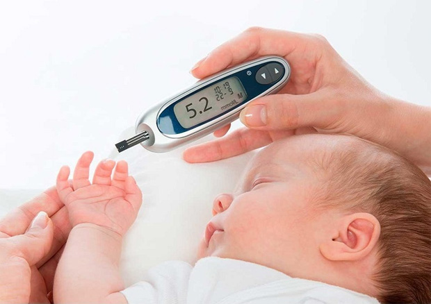 У спящего малыша берут немного крови из пальца для диагностики уровня сахара