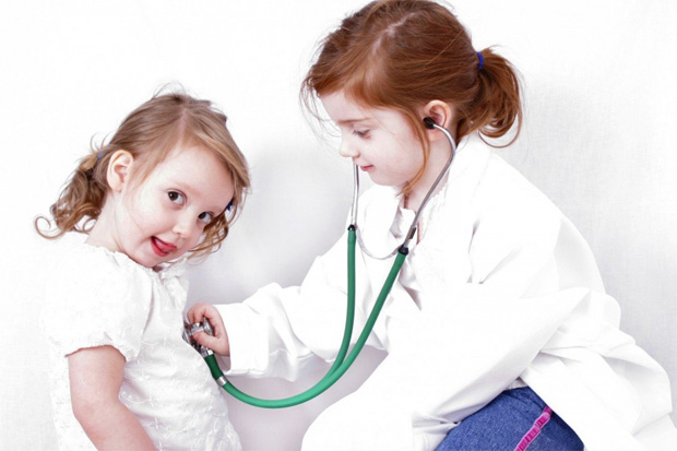 Две жизнерадостные девочки сестрички играют в доктора со стетоскопом