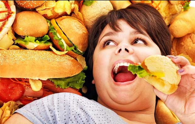 Полная девушка старше тридцати лет лежит на фастфуде с гамбургером в руке