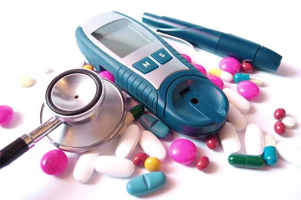 На столе лежит прибор для измерения уровня сахара, ручка-игла, стетоскоп и лекарства