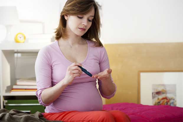 Беременная женщина делает себе прокол в пальце для проверки уровня сахара в крови