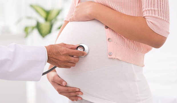 Два прослушивает стетоскопом сердцебиение ребенка в утробе беременной женщины