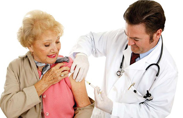 Врач делает пожилой пациентке в розовой блузке укол инсулина в плечо