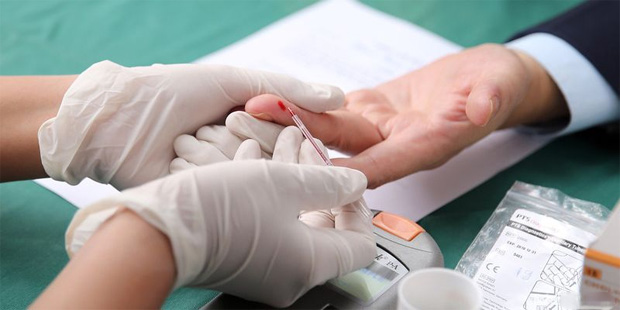 Лаборант в медицинских перчатках берет немного крови у мужчины на анализ