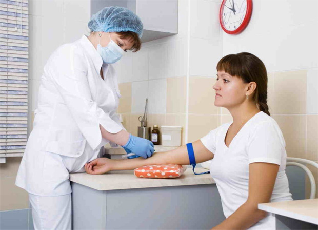Женщина сидит в процедурном кабинете и готовится к забору крови из вены