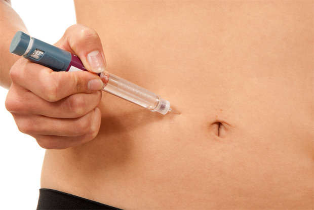 Девушка специальной ручкой с иглой делает укол инсулина себе в живот